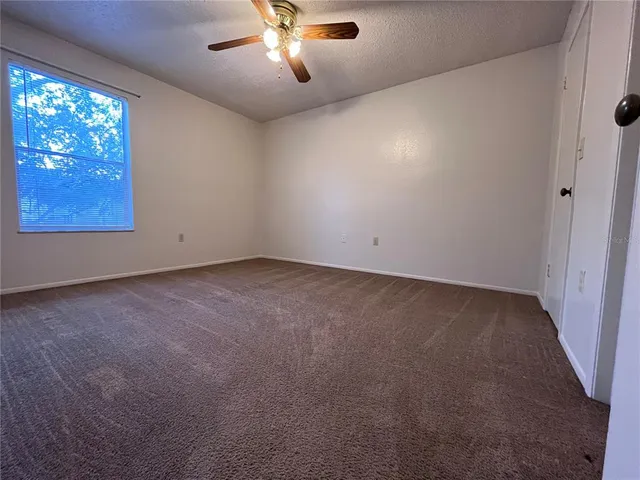 an empty room with windows and chandelier fan