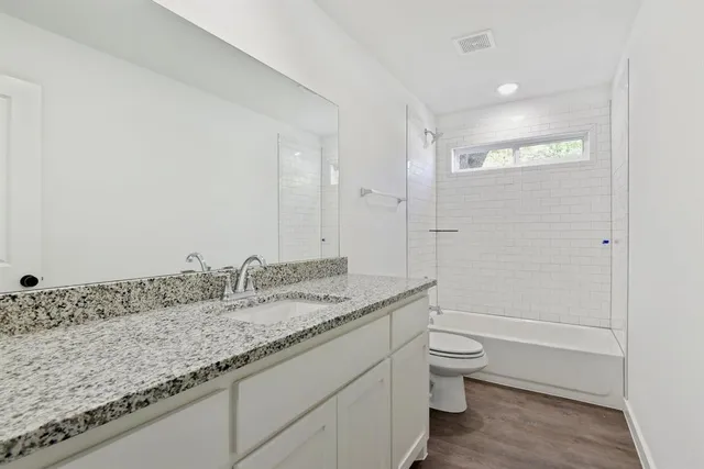 a bathroom with a granite countertop sink a toilet and shower