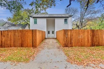 a view of a house with a wooden fence and a large tree