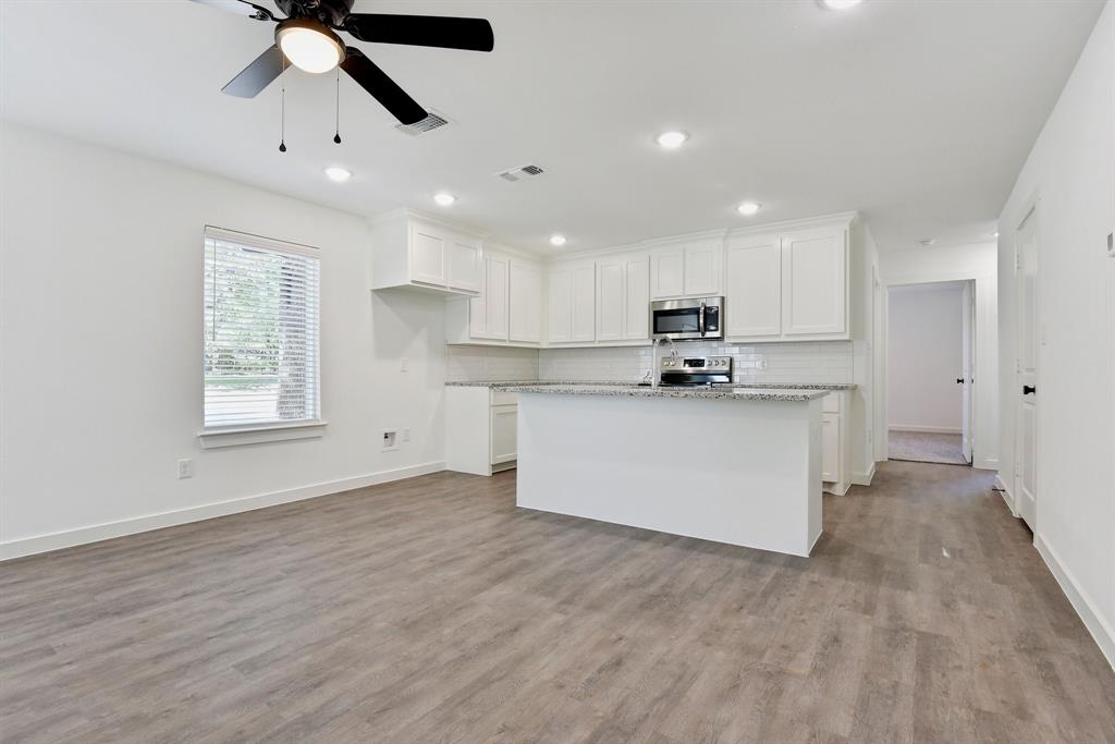 103 East Bond Street Denison, TX 75021 - Photo 4 of 21 a kitchen with stainless steel appliances granite countertop a stove a sink dishwasher and a refrigerator with wooden floor