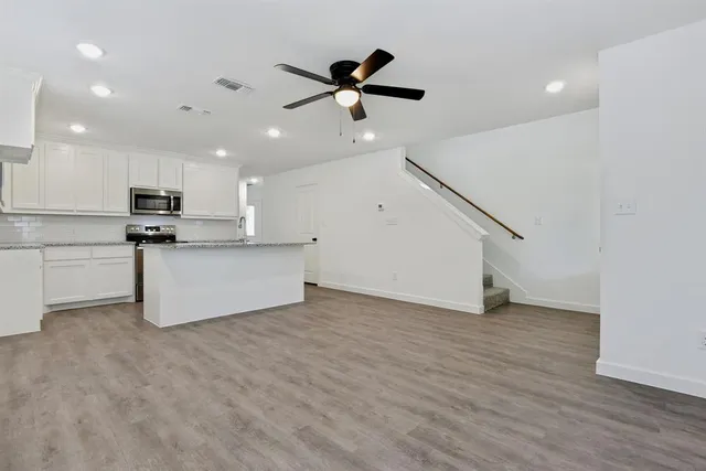 a view of kitchen with stainless steel appliances wooden floor and living room view