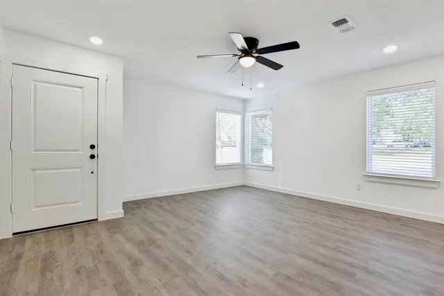 a view of empty room with wooden floor and fan