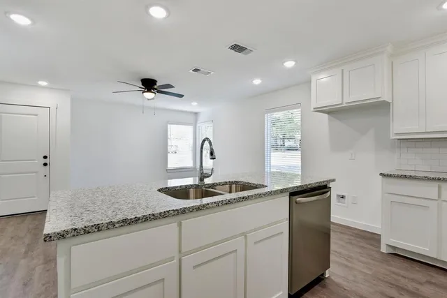 a kitchen with granite countertop a sink and white cabinets