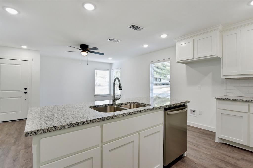 103 East Bond Street Denison, TX 75021 - Photo 10 of 21 a kitchen with granite countertop a sink and white cabinets