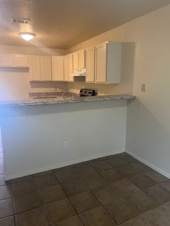a view of kitchen with granite countertop white cabinets and a sink