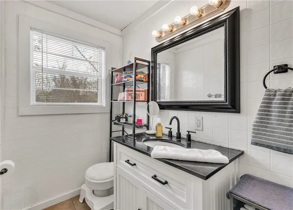 a bathroom with a toilet a sink a mirror and a window