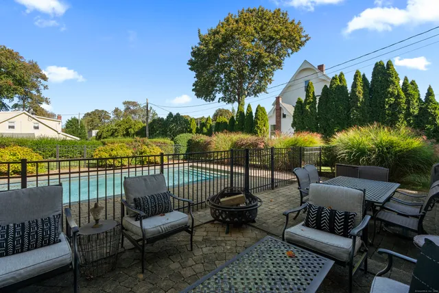 a view of a patio with couches chairs and a table and chairs with wooden floor and fence