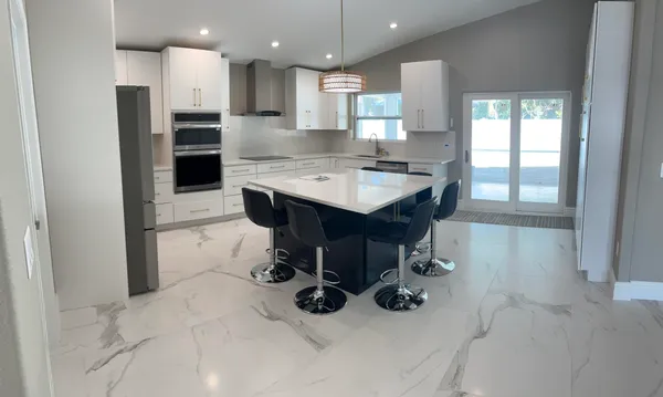 a kitchen with stainless steel appliances kitchen island granite countertop a refrigerator and a sink