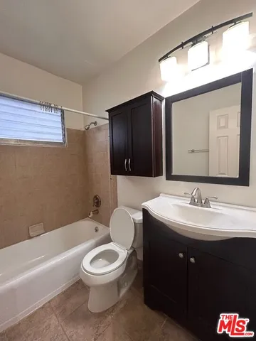 a bathroom with a toilet a sink a tub and a mirror
