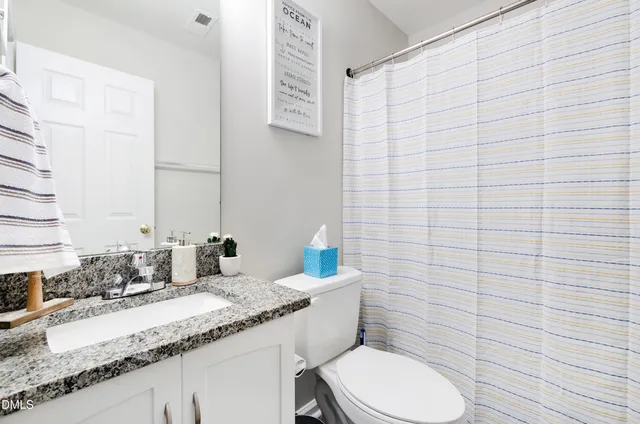 a bathroom with a granite countertop toilet sink and mirror
