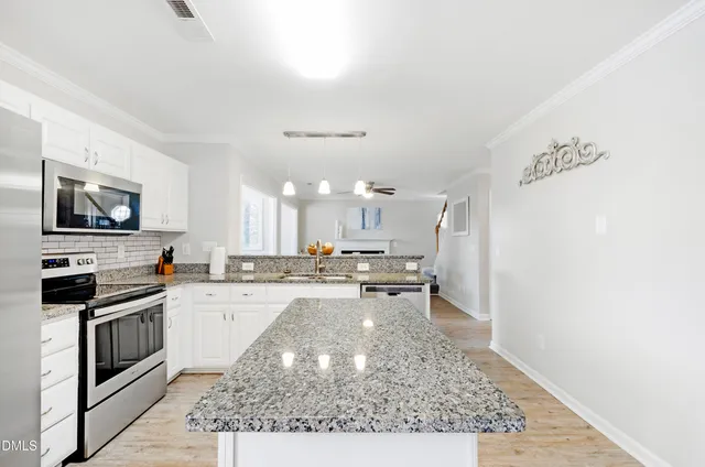 a kitchen with stainless steel appliances granite countertop a stove top oven a sink a counter space and cabinets