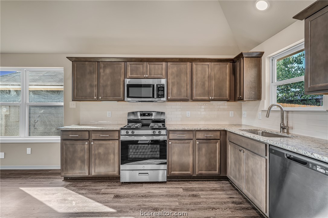 2766 Messenger Way Bryan, TX 77803 - Photo 6 of 12 a kitchen with stainless steel appliances granite countertop a stove a sink dishwasher and a microwave oven with cabinets