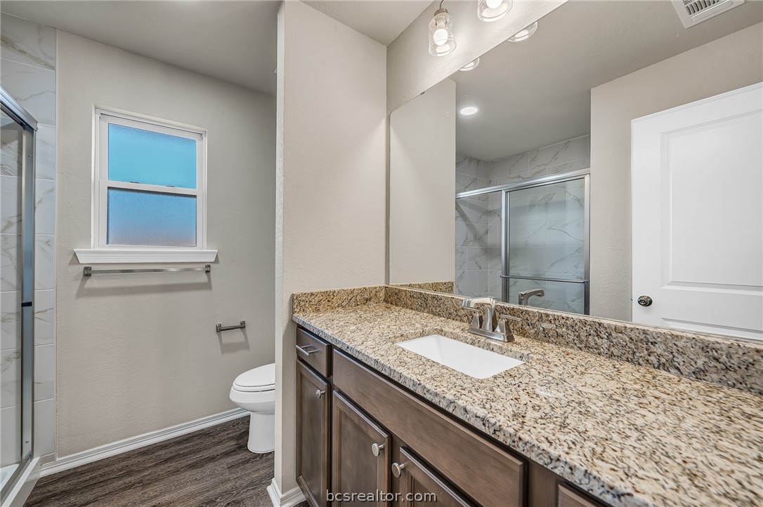2766 Messenger Way Bryan, TX 77803 - Photo 10 of 12 a bathroom with a granite countertop sink a toilet and a vanity