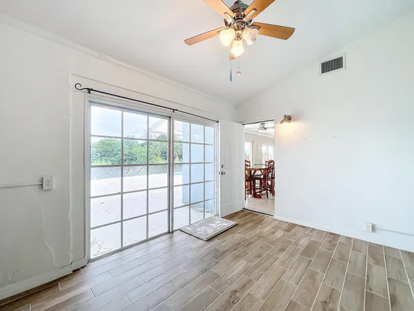 an empty room with wooden floor chandelier fan and windows