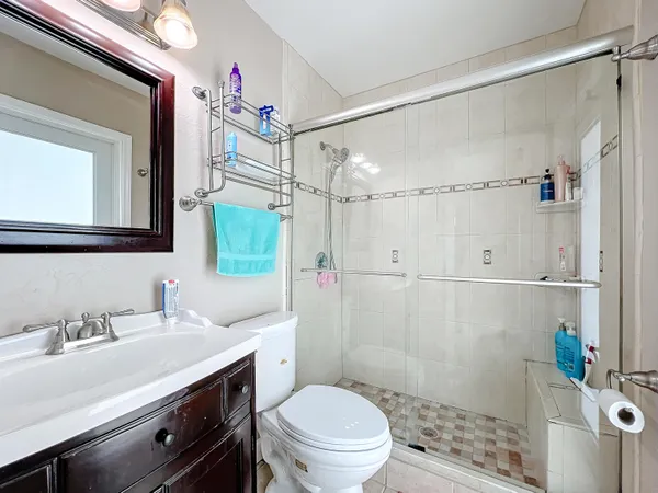 a bathroom with a sink a toilet a mirror and shower