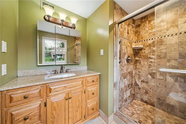a bathroom with a granite countertop sink a mirror a vanity and shower