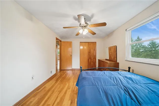 a view of an empty room with window and wooden floor