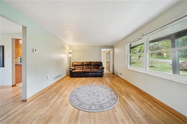 a view of a room with wooden floor a ceiling fan and windows