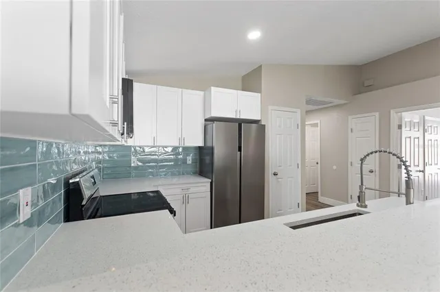 a kitchen with stainless steel appliances kitchen island granite countertop a refrigerator a stove and a sink with wooden cabinets