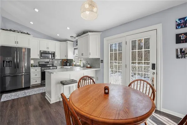 a kitchen with stainless steel appliances granite countertop a refrigerator a stove a sink a dining table and chairs