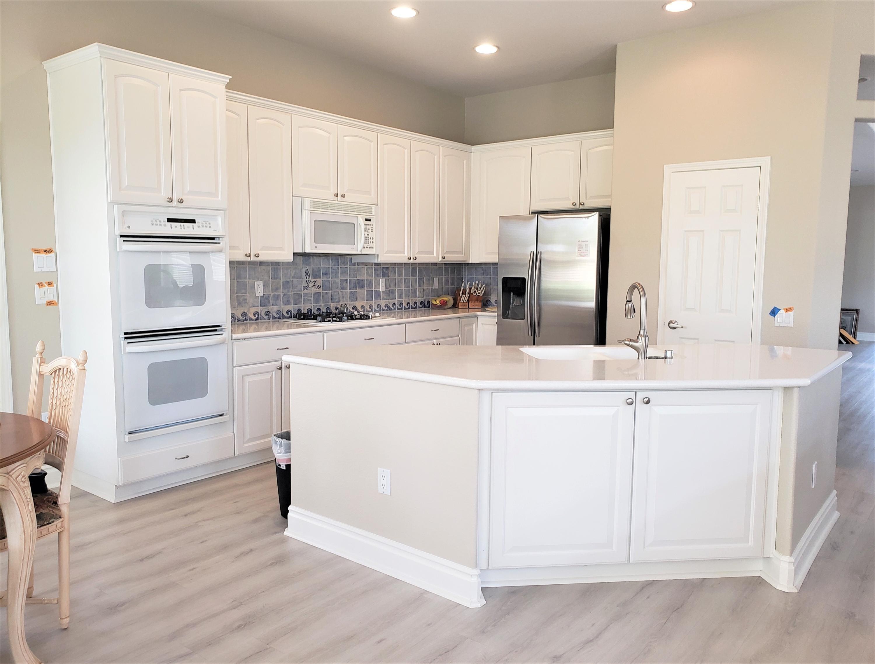 44017 Royal Troon Drive Indio, CA 92201 - Photo 10 of 33 a kitchen with kitchen island granite countertop white cabinets and white appliances