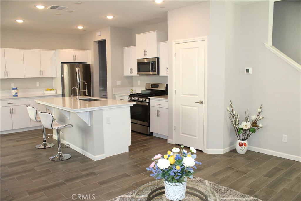 2060 North Walker Lane Clovis, CA 93619 - Photo 7 of 17 a kitchen with stainless steel appliances kitchen island granite countertop a refrigerator a stove a sink dishwasher and white cabinets with wooden floor