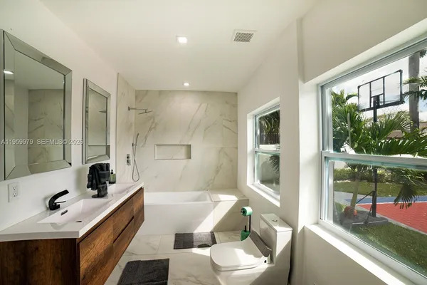 a bathroom with a bathtub toilet sink vanity and windows