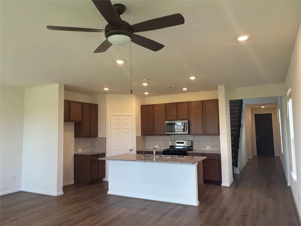 a kitchen with stainless steel appliances granite countertop a refrigerator a stove top oven a sink and dishwasher with wooden floor