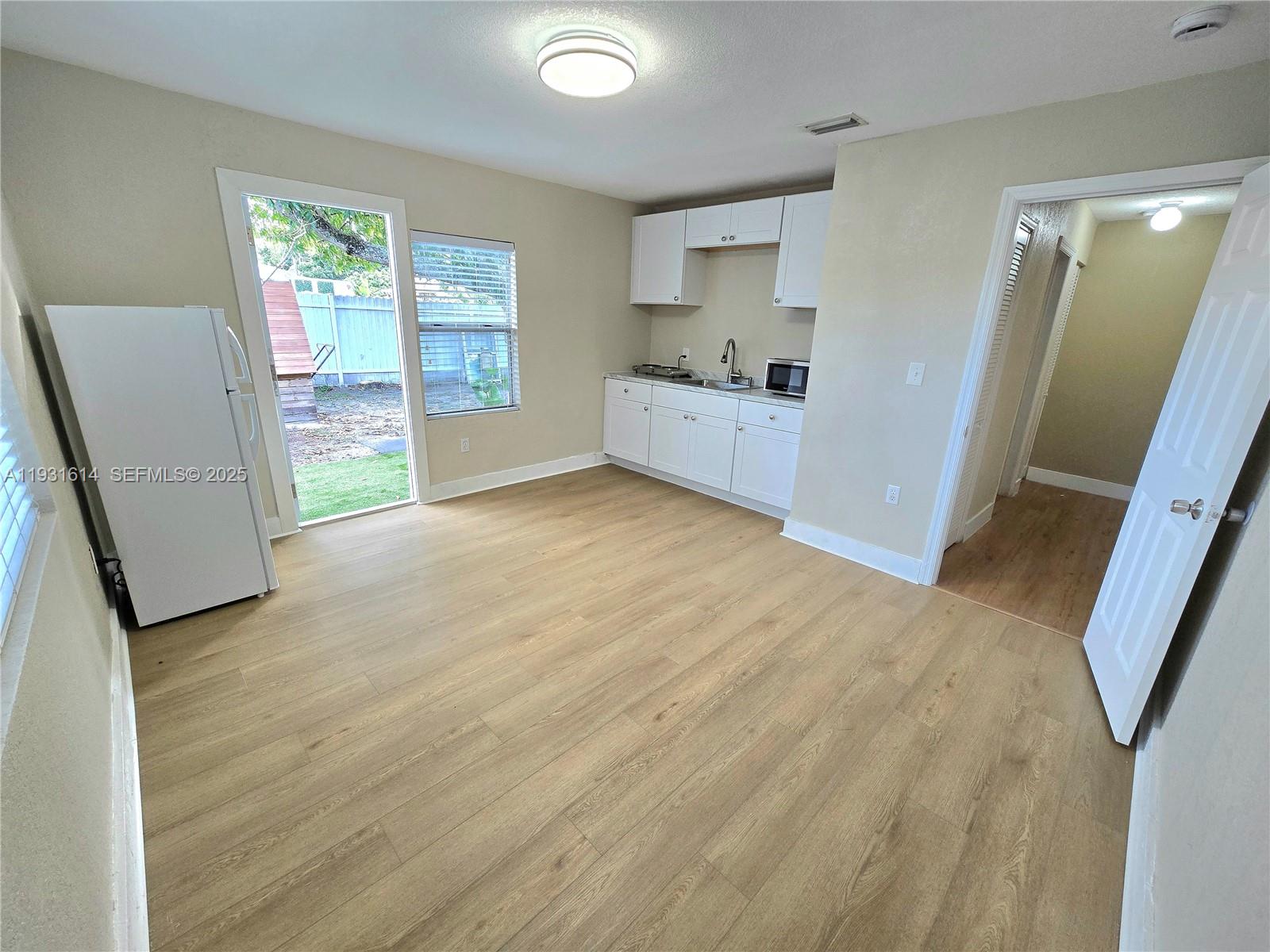 a view of an empty room with a window and a kitchen