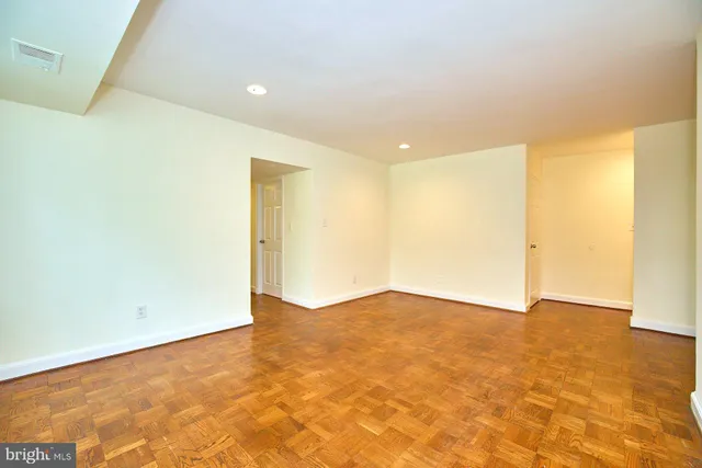 an empty room with wooden floor and fan
