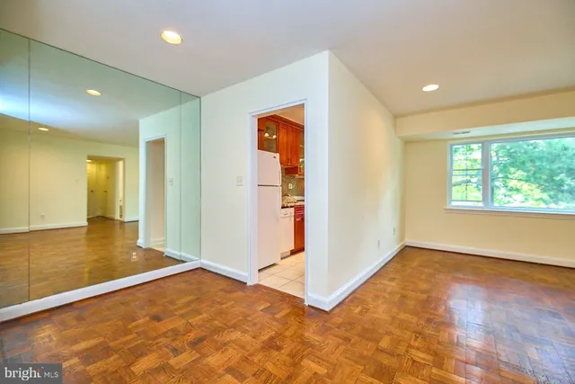 a view of an empty room with wooden floor and a window