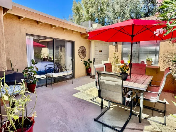 a view of a patio with a dining table and chairs under an umbrella
