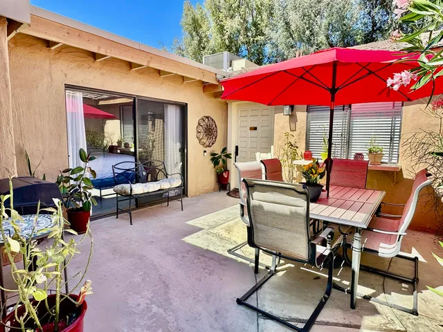 a view of a patio with a dining table and chairs under an umbrella