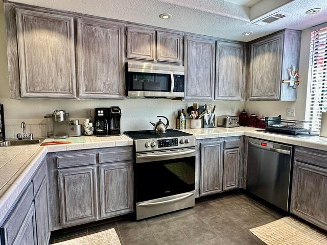 a kitchen with stainless steel appliances granite countertop a sink a stove a microwave oven and cabinets