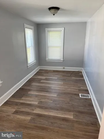 a view of empty room with window and wooden floor