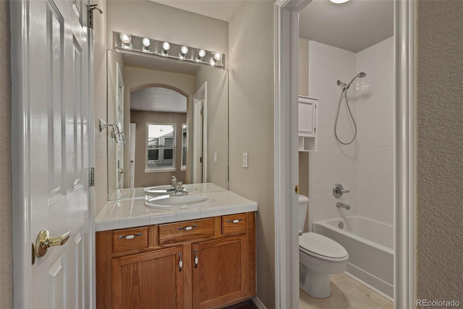 6677 South Forest Way, Unit D Centennial, CO 80121 - Photo 28 of 35 a bathroom with a granite countertop sink toilet a shower and a mirror