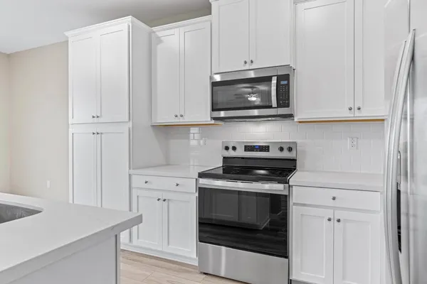 a kitchen with white cabinets and stainless steel appliances