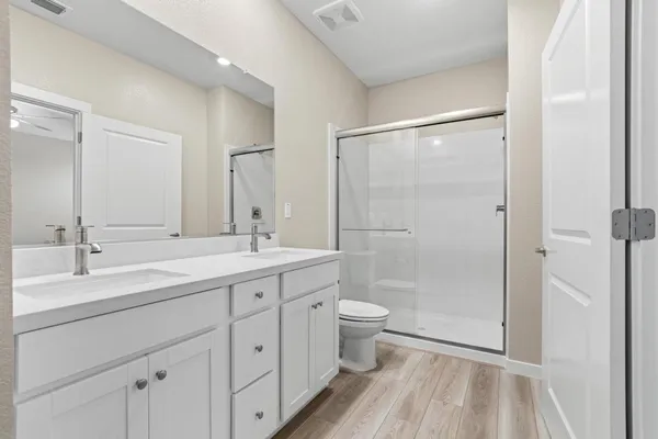 a bathroom with a double vanity sink toilet and shower