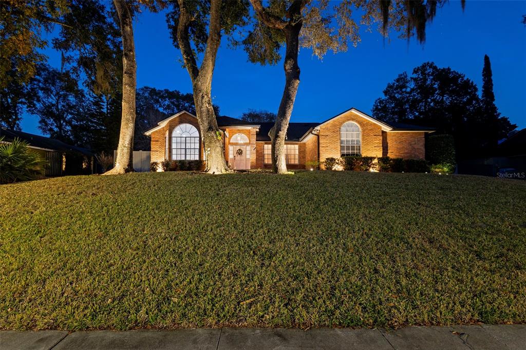a view of a house with a big yard and large tree
