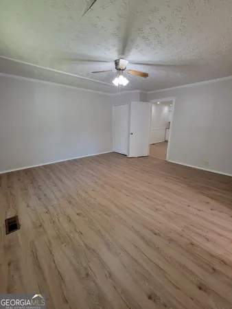 an empty room with wooden floor ceiling fan and windows