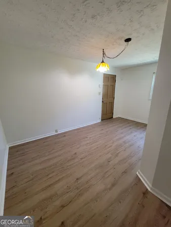 an empty room with wooden floor and natural light