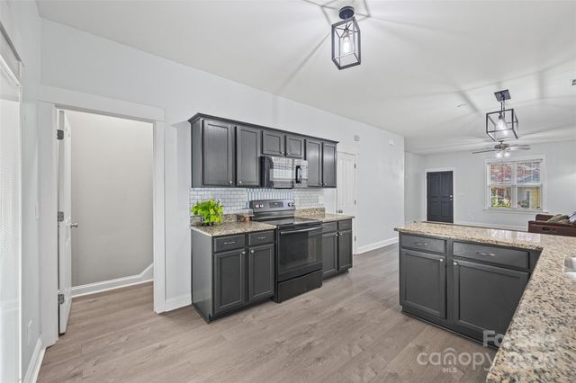 a kitchen with stainless steel appliances granite countertop a stove a sink dishwasher a refrigerator and a oven with wooden floor