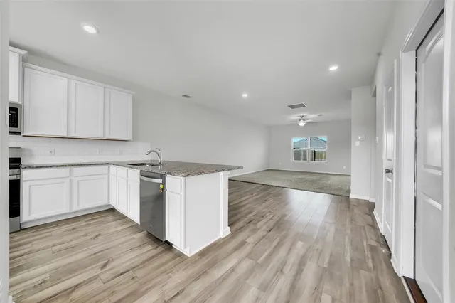 a kitchen with wooden floors and white cabinets