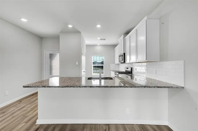 a kitchen with granite countertop a sink a stove and cabinets