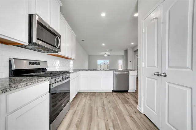 a large kitchen with stainless steel appliances granite countertop a stove a sink and a microwave