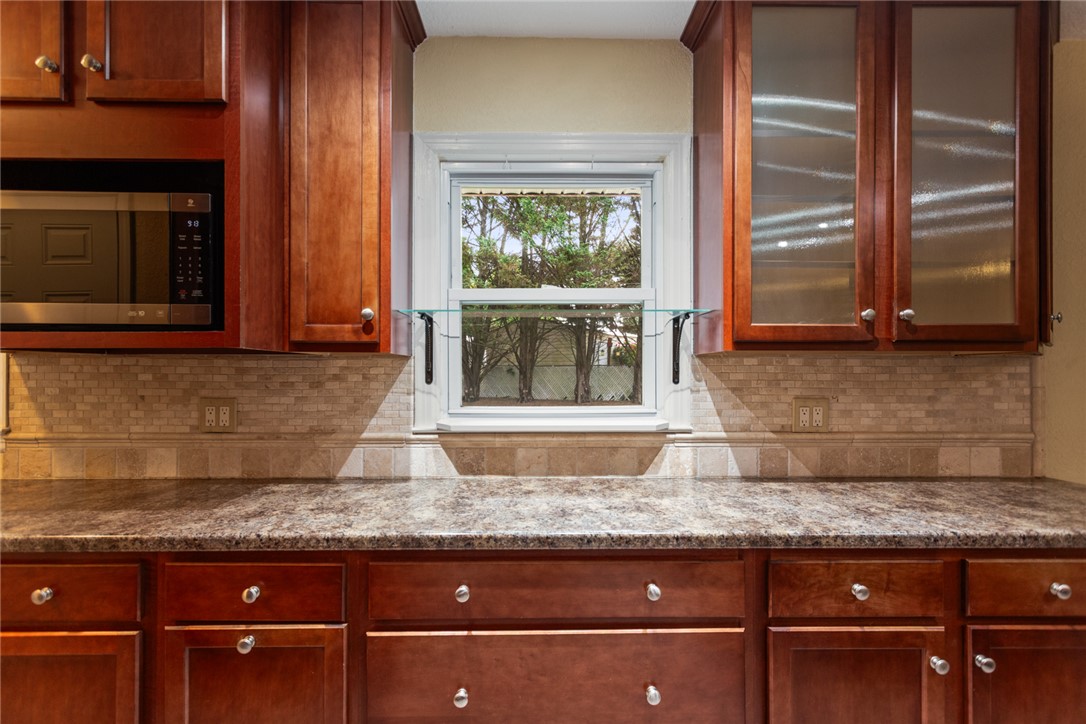 202 Keowee Trail Seneca, SC 29672 - Photo 10 of 35 This kitchen showcases ample cabinetry, a microwave, and a bright window above solid countertops and a tiled backsplash.