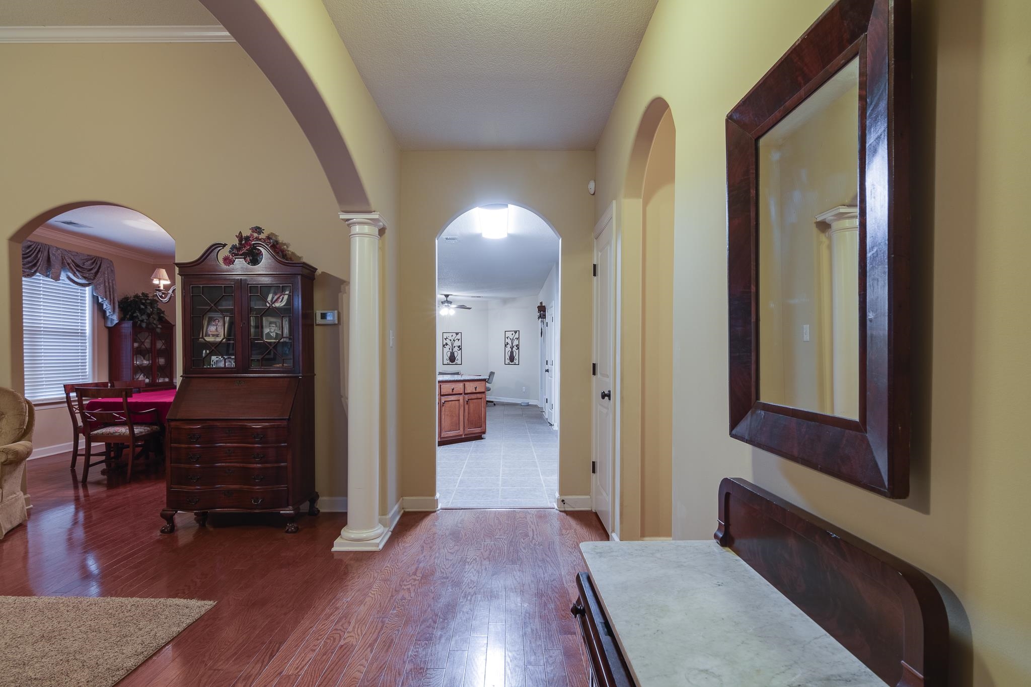 Corridor with ornate columns, wood-type flooring, and crown molding