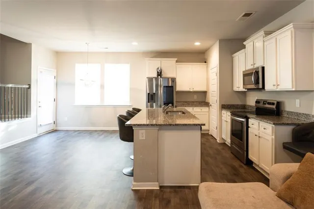 a kitchen with kitchen island granite countertop a sink cabinets and wooden floor
