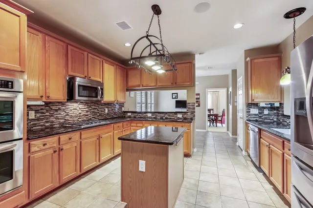 a kitchen with stainless steel appliances granite countertop a stove top oven a sink a counter space and cabinets
