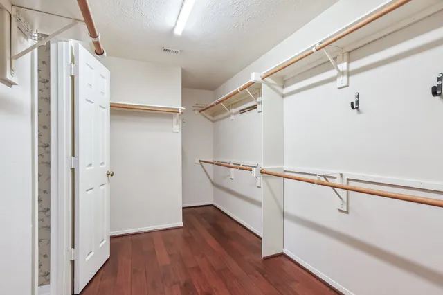 a view of an empty walk in closet with wooden floor